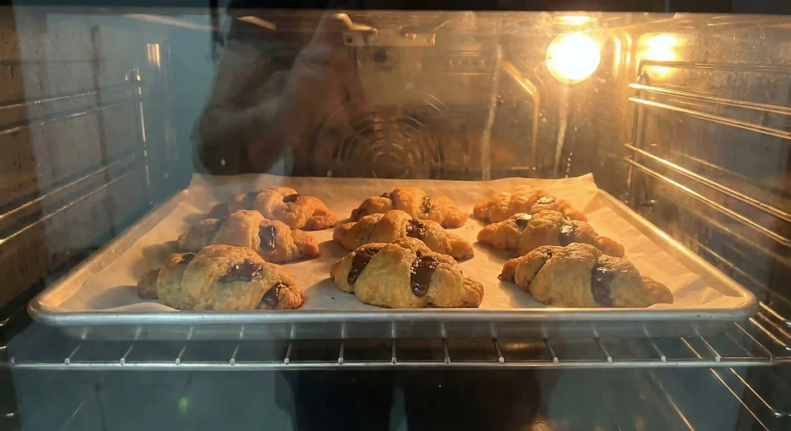 Crookies baking in an oven on a lined tray