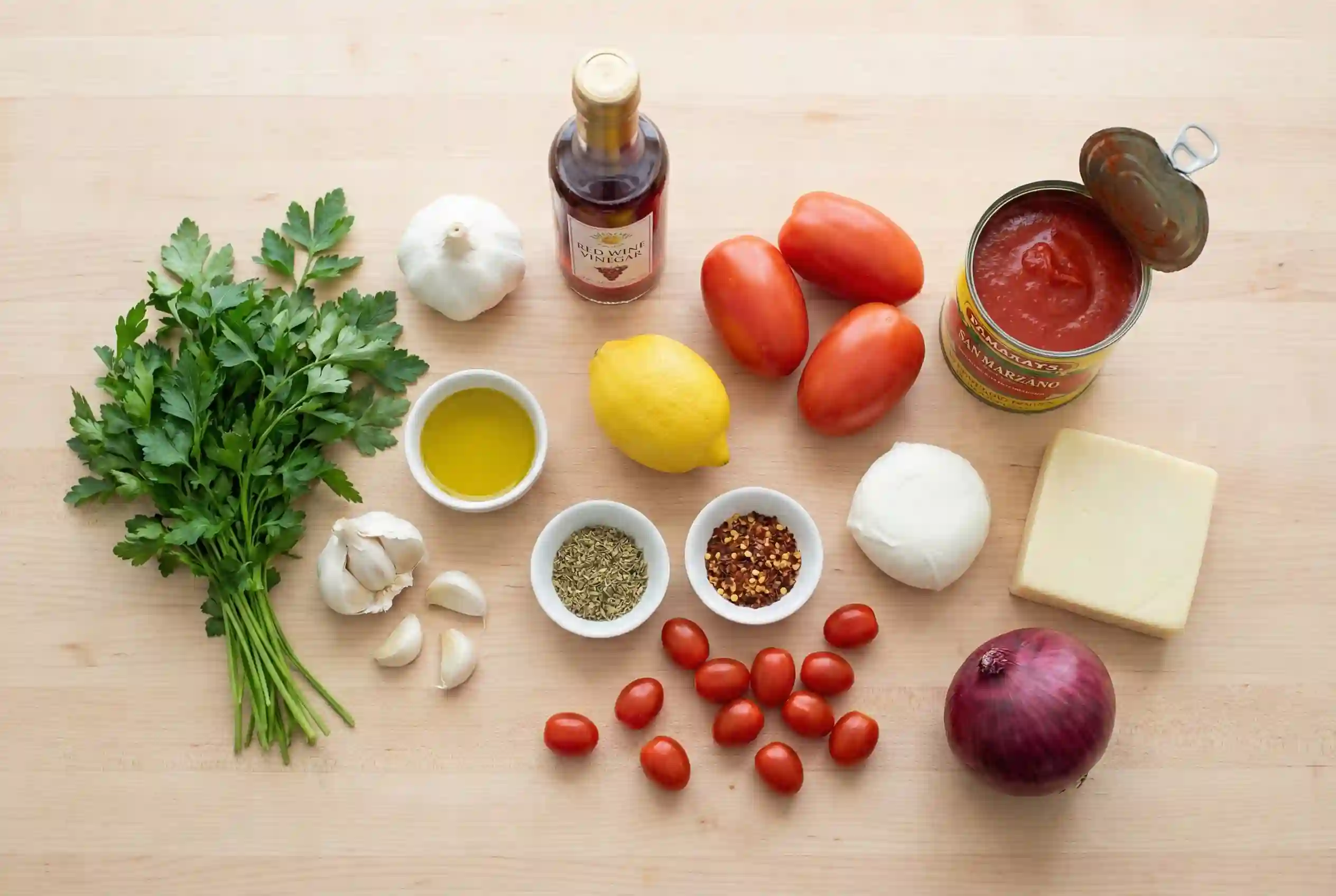 Ingredients for chimichurri tomato pizza including parsley garlic olive oil and tomatoes
