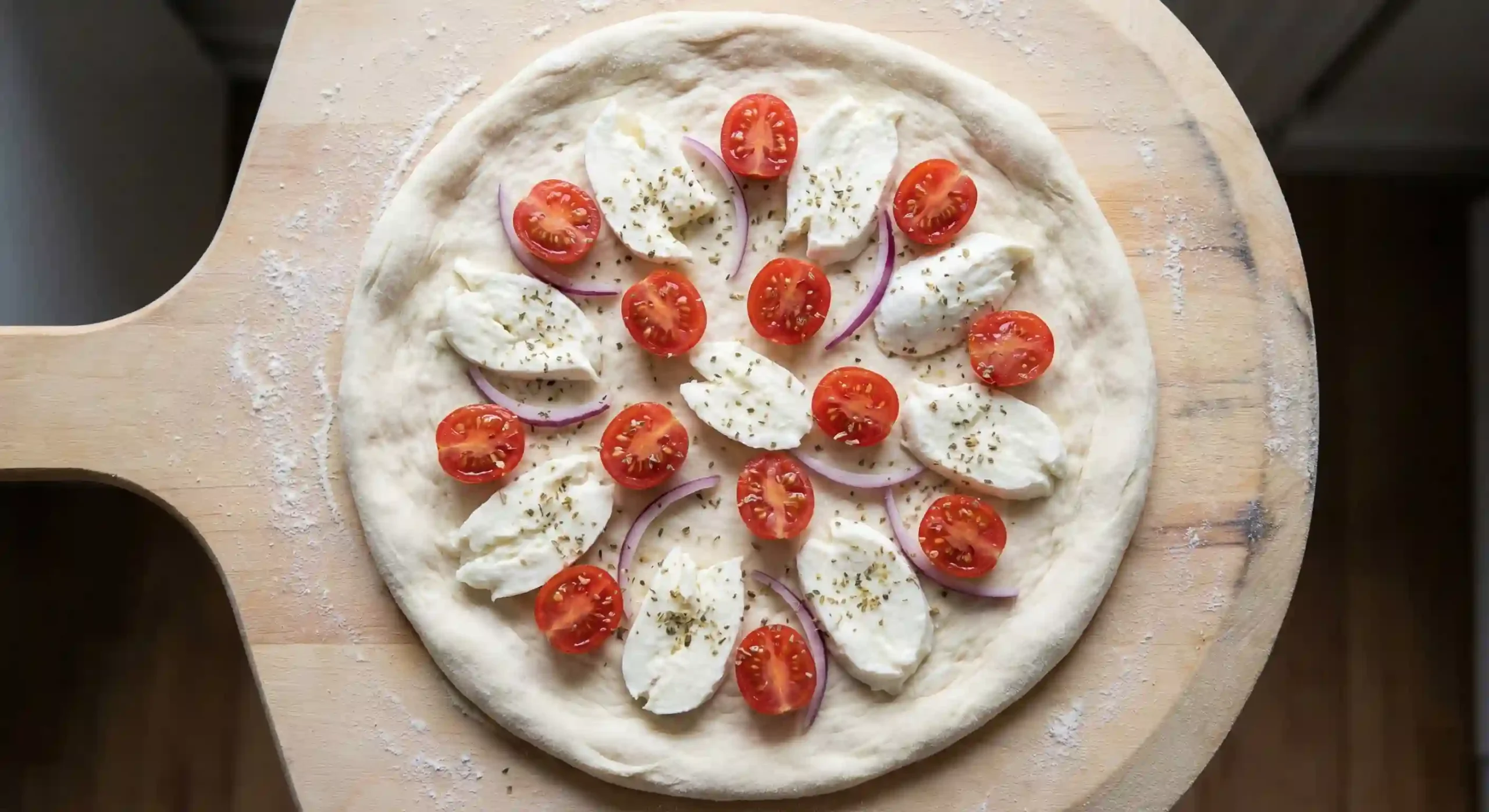 Pizza toppings spaced evenly with tomatoes onion and mozzarella to avoid sogginess