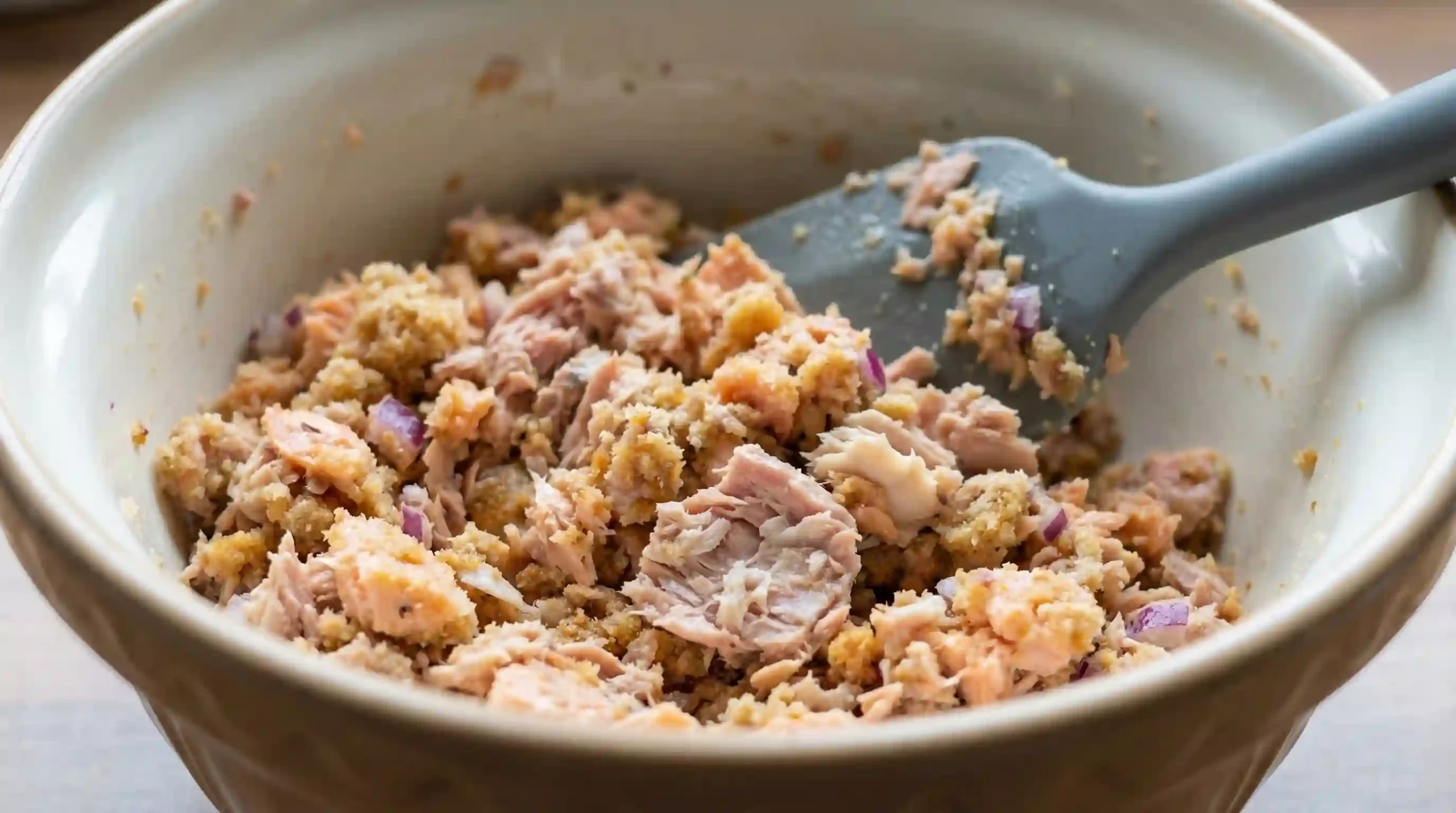 Tuna salmon loaf mixture being folded together in a mixing bowl